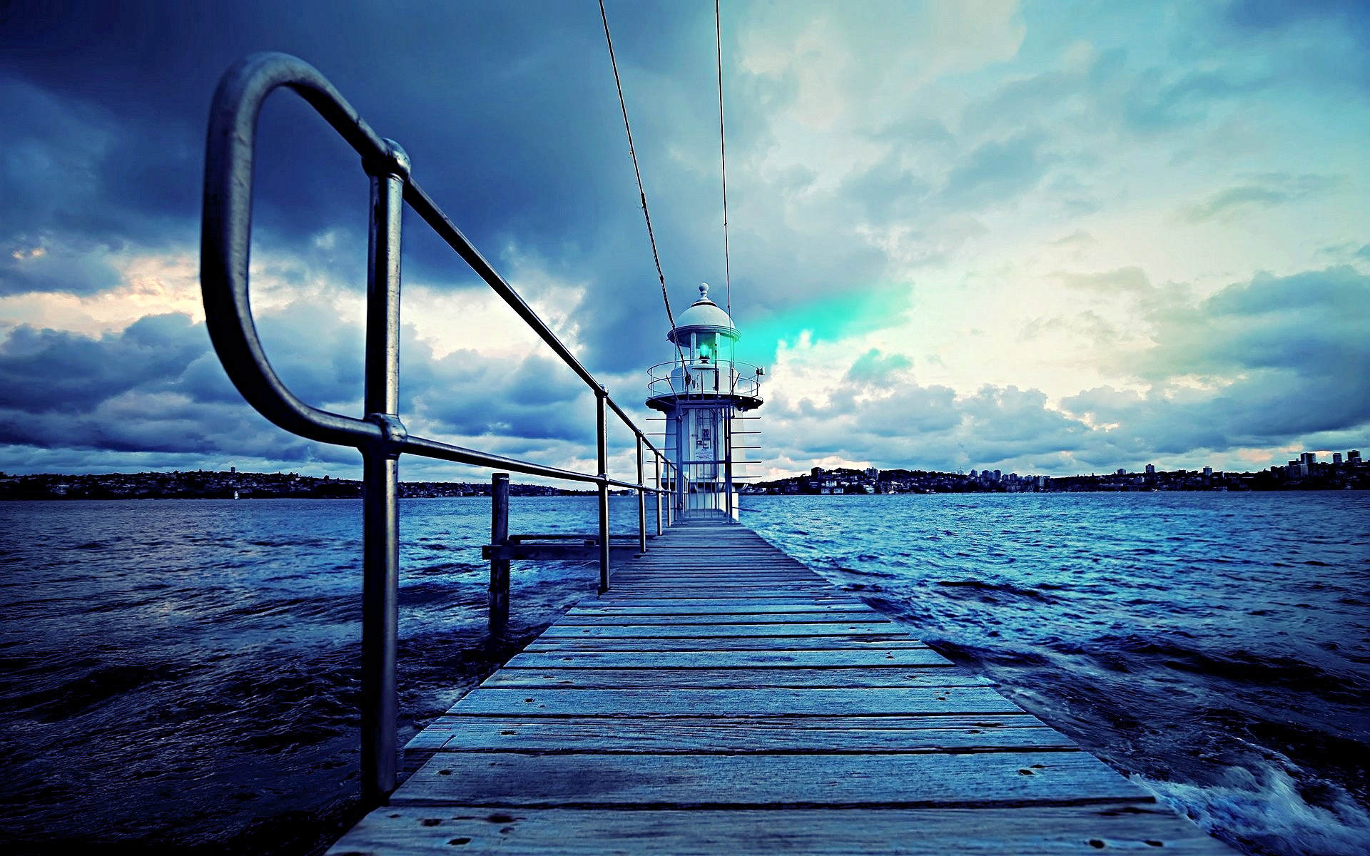 A bold charcoal drawing of a small lighthouse at the end of a wooden pier extending into the sea under a dramatic cloudy sky.